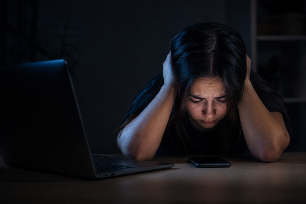 Desafios mortais: jovem sobrecarregada diante de celular e notebook