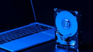 O que é HD: disco rígido aberto com componentes internos ao lado de um laptop